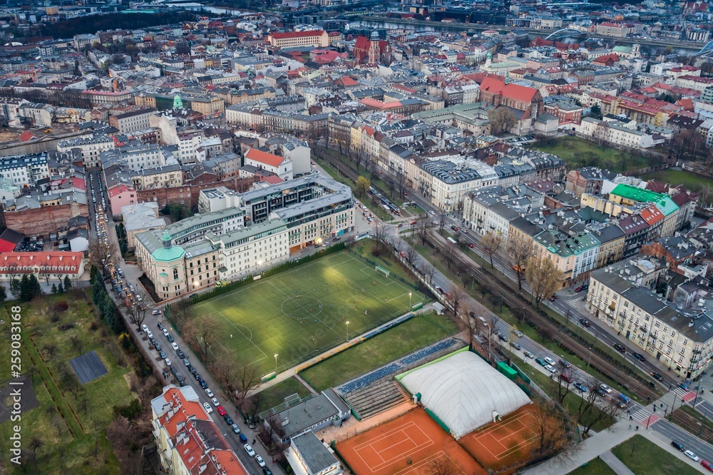 Aerial drone view on Football match on playing field court in the middle of Cracow city