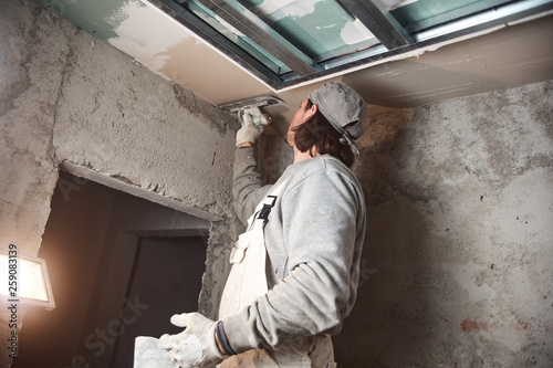 Worksman plastering gypsum walls inside the house. © astrosystem