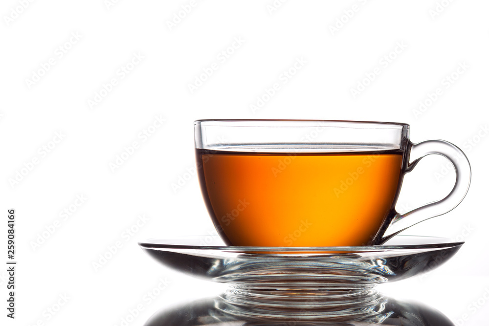 A cup of black tea and a spoon on a white table with reflection A cup of black tea and a spoon on a white table with reflection