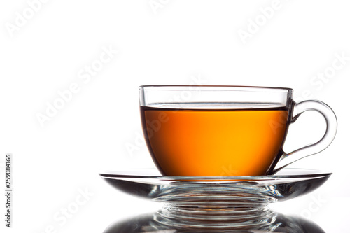 A cup of black tea and a spoon on a white table with reflection