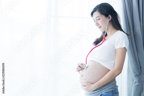 Free Download Portrait of Beautiful young pregnant women using stethoscope listening to her tummy.Pregnancy health care preparing for baby concept.Motherhood among teenage mother. - GFXLoad