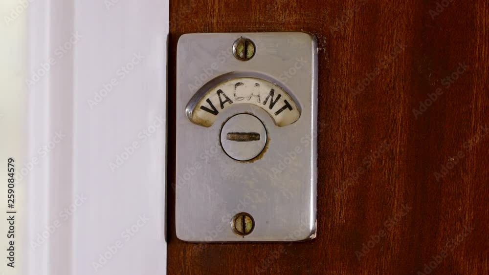 Closeup of someone entering a public toilet / bathroom and closing the wooden door. The sign changes from vacant to engaged. Closeup of someone entering a public toilet / bathroom and closing the wooden door. The sign changes from vacant to engaged.