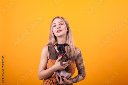 Beautiful women with casual dress and her adorable puppy over ellow background photo