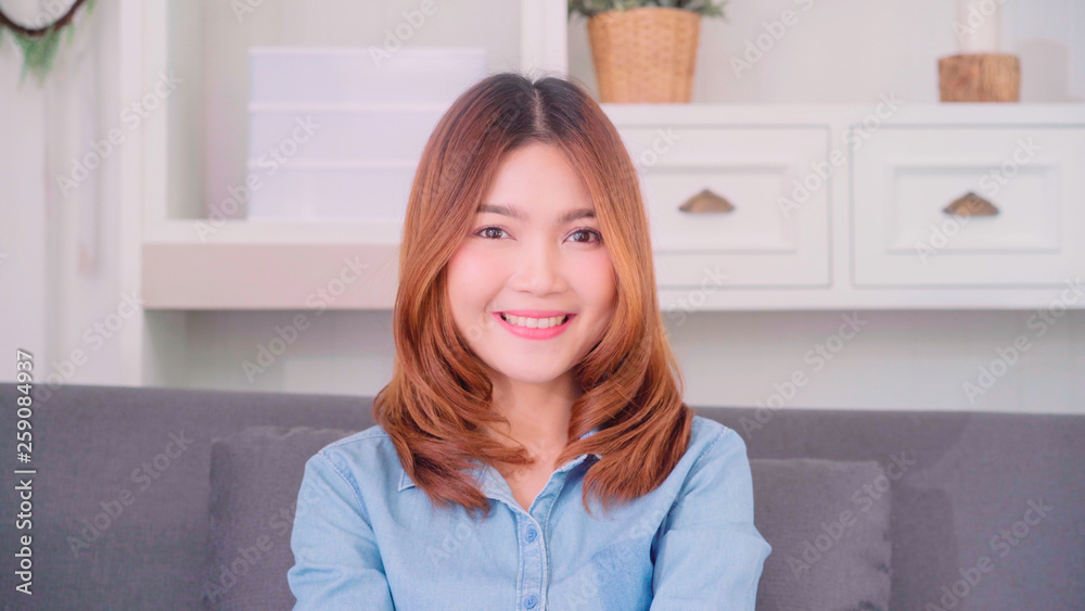 Teenager Asian woman feeling happy smiling and looking to camera while relax in her living room at home. Beautiful Asian young female using relax time at home concept. Teenager Asian woman feeling happy smiling and looking to camera while relax in her living room at home. Beautiful Asian young female using relax time at home concept.
