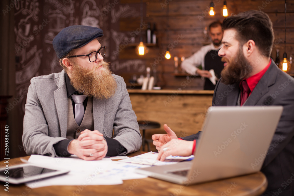 Handsome bearded coworkers having a conversation in a coffee shop Handsome bearded coworkers having a conversation in a coffee shop