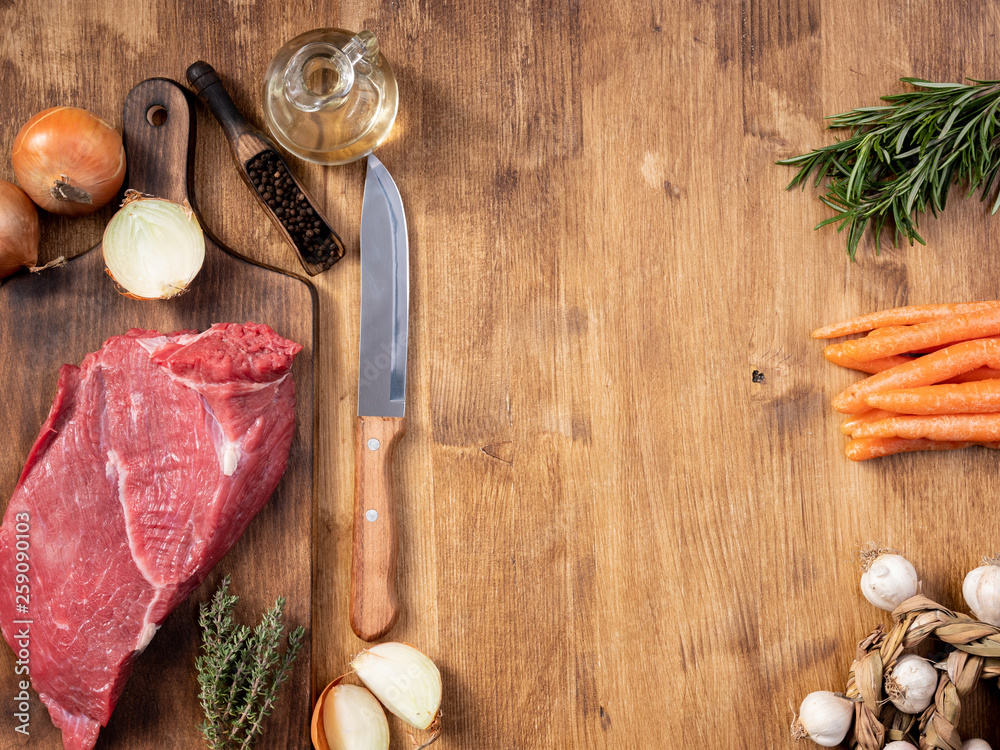 Chef knife next to a big chunk of red meat fresh vegetables Chef knife next to a big chunk of red meat fresh vegetables