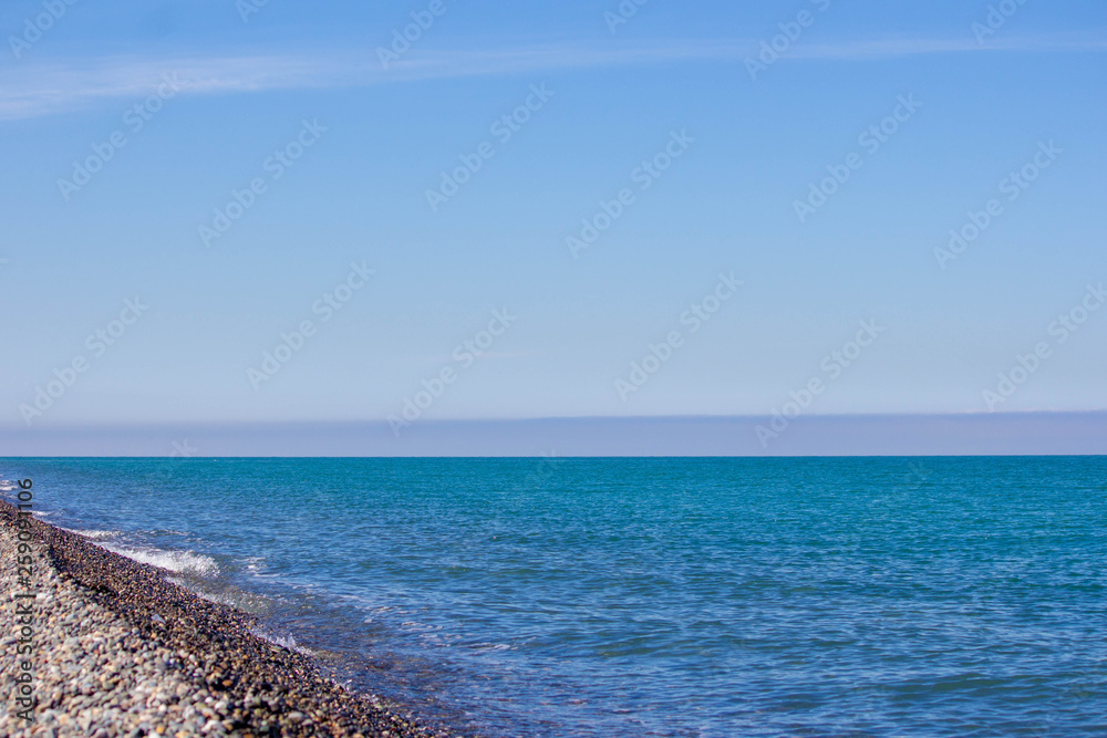 Natural concept. Blue sea, sea coast, small stones.