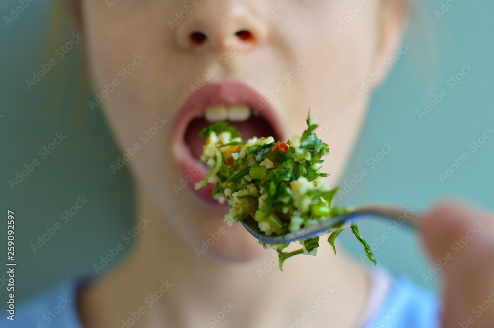 Crop close up shot of girl eating salad with a fork Crop close up shot of girl eating salad with a fork