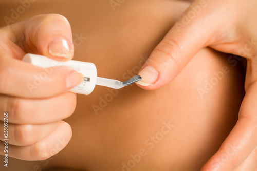 woman applying a nail polish on her fingernails