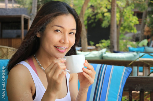 A woman is drinking coffee with a happy smile.