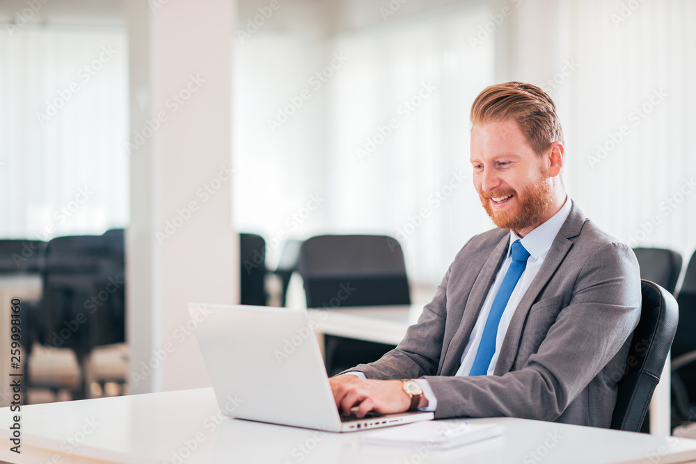 Ginger businessman working on laptop at workplace. Ginger businessman working on laptop at workplace.