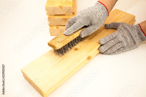 Hand wire brush men's hands in protective gloves on vintage wooden Board. Aging wooden boards by brushing. White background. Create fotofone