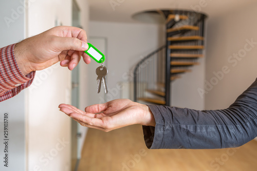 Der Wohnungsschlüssel wird übergeben, im Hintergrund ist eine leere Maisonette Wohnung zu sehen
