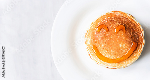 fresh classic pancake stacked in stack on gray background with place for text. with a smile painted with honey and maple syrup photo
