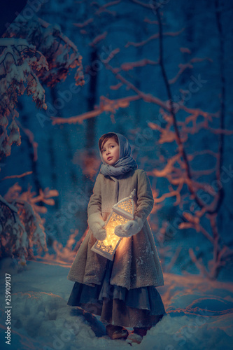Girl with lantern in dark winter forest