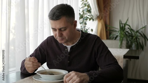 The man at the cafe table is slowly eating soup. Business lunch
