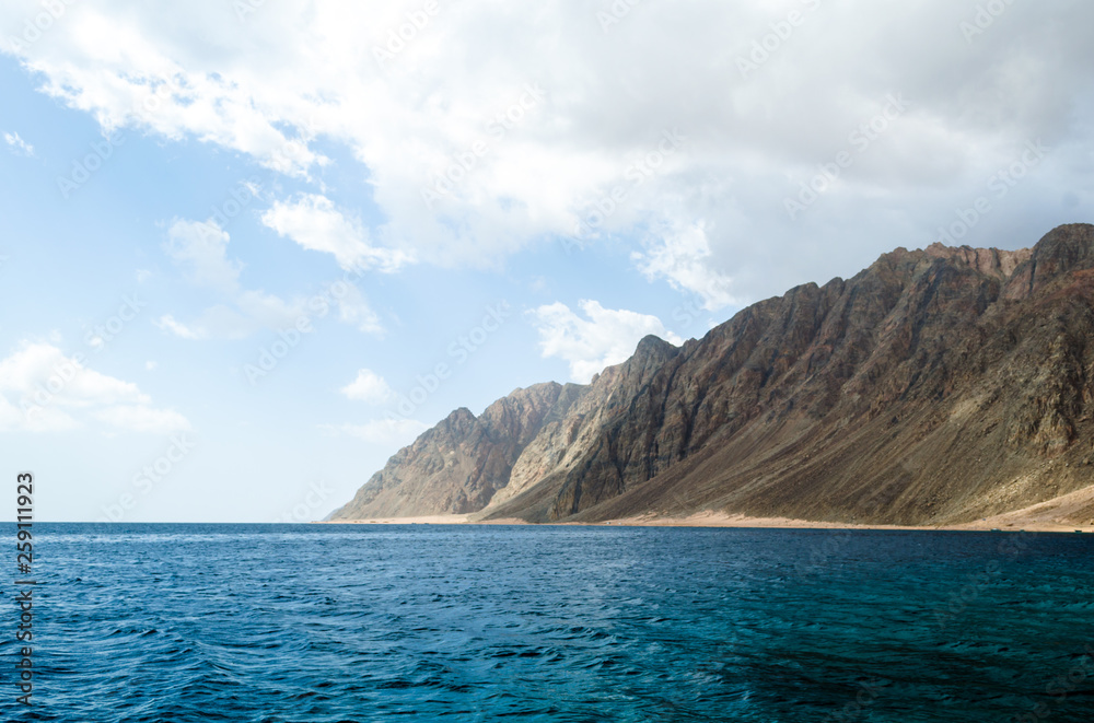 blue sea and high rocky mountains against the sky and clouds in Egypt Dahab South Sinai