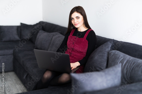 Free Download Happy pretty woman using laptop sitting on cosy sofa at home - GFXLoad
