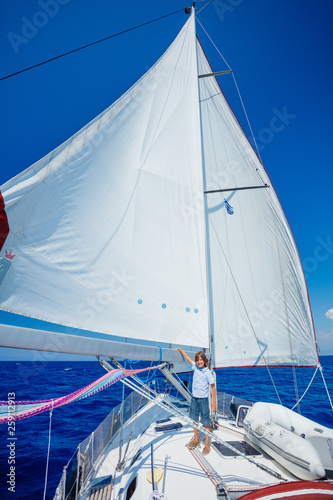 Little boy on board of sailing yacht on summer cruise. Travel adventure  yachting with child on family vacation.