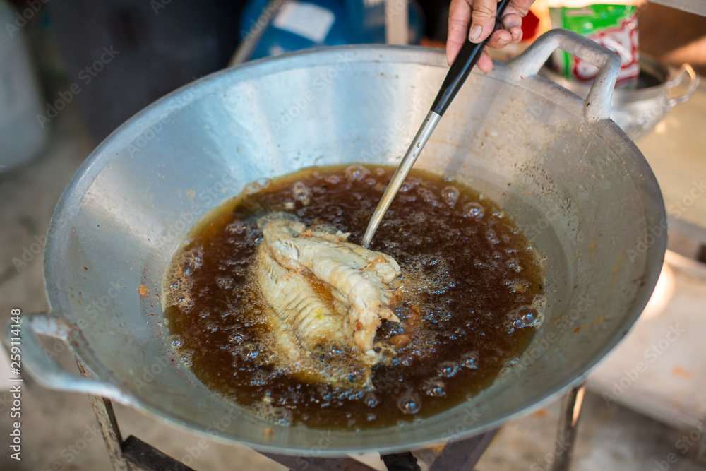 Chef cooking deep-fried fish in the big pan to Chinese banquet food preparation. fat from trans-fat concept. disease from cholesterol and Trans-fatty concept. image for copy space and objects. Chef cooking deep-fried fish in the big pan to Chinese banquet food preparation. fat from trans-fat concept. disease from cholesterol and Trans-fatty concept. image for copy space and objects.