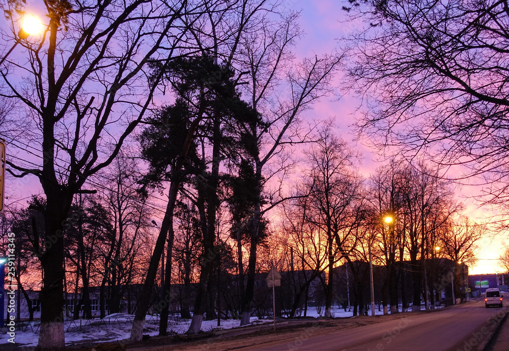 Purple sky Early morning in a small town. Lights are burning. Empty road. Dramatic sunset background. Russia.