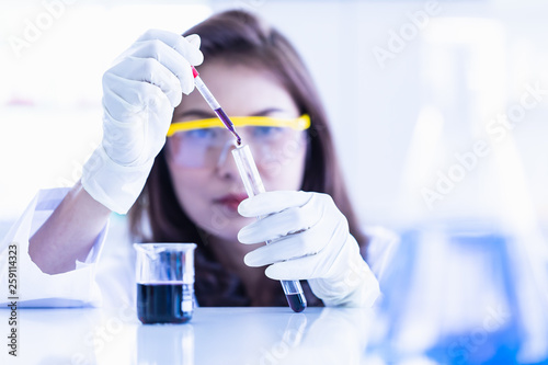 Scientist dropping purple liquid to test tube.. photo