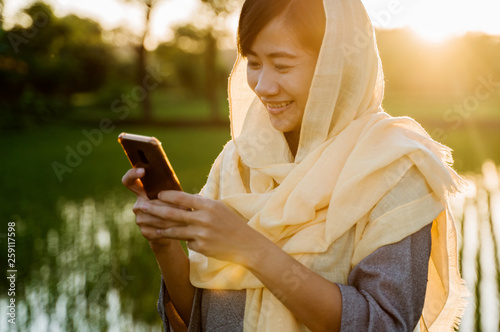 muslim woman with hijab using mobile phone outdoor