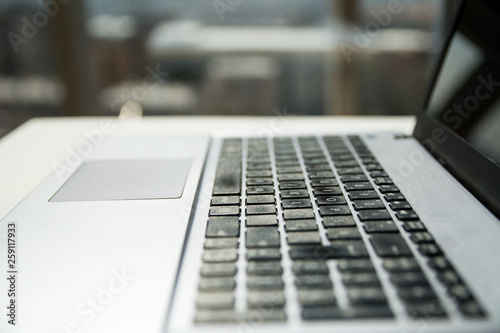 Laptop in Black and Silver Color with Reflection. City panorama in the background. Close Up concept