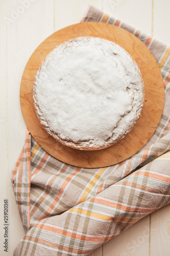 delicious tart sprinkled with white powdered sugar or cream. Photo from above. The pie is located on a stand with a tablecloth on a white table