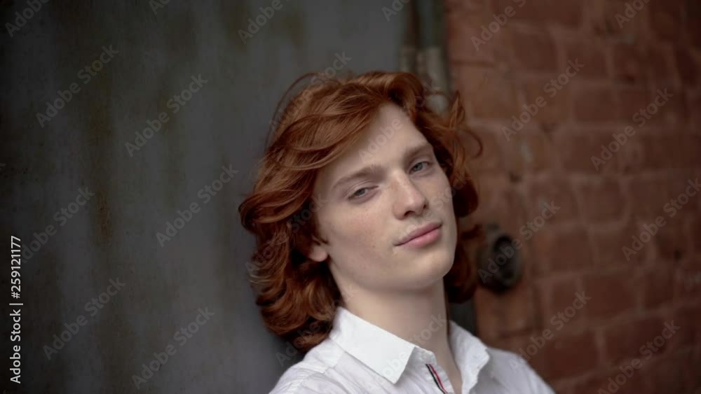 Red-Haired Young Guy in a White Shirt Posing on the Street. Red-Haired Young Guy in a White Shirt Posing on the Street.