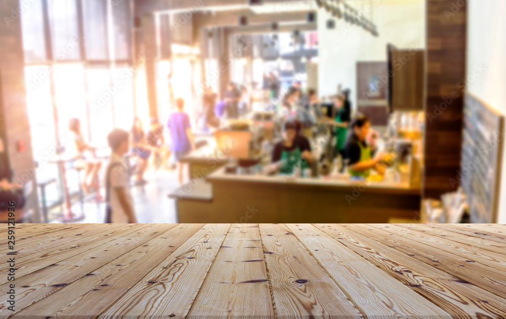 Perspective brown wooden board empty table in front of blurred people in store shop, coffee shop, restaurant morning time with sunlight on background - can be used for display or montage your products