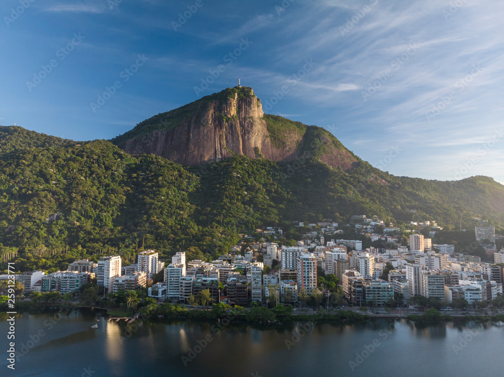 Corcovado mountain in Rio de Janeiro seen from the side on top of which resides the Christ statue with in the foreground the city lake Lagoa Rodrigo de Freitas on a bright sunny morning at sunrise