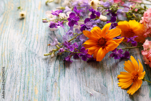 bouquet of yellow, purple and pink flowers on a wooden background, front view