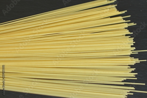 raw fresh spaghetti, thin yellow on black background 