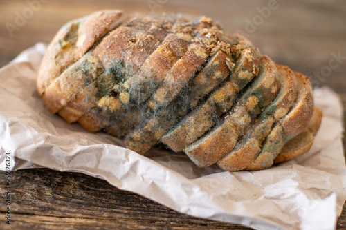 Moldy bread on the wooden rustic table , scarcity