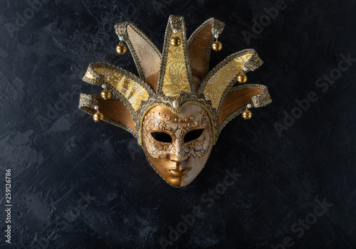 Venetian mask on a black background. Gilded mask on a stone black wall background.