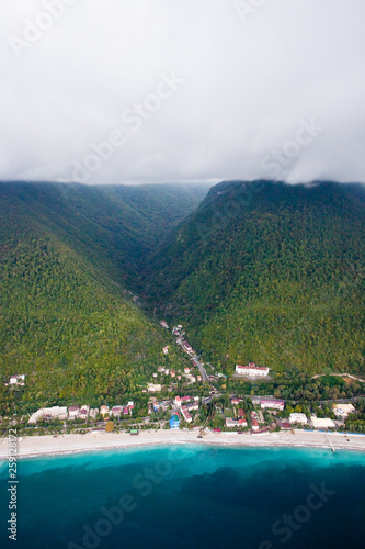 Clouds on the mountains. Beautiful green hills with hotels and hotels by the sea, rich bright colors. Aerial view in Abkhazia