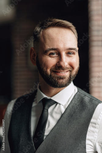 successful young businessman in a vest and tie. with a stylish and stylish haircut and beard