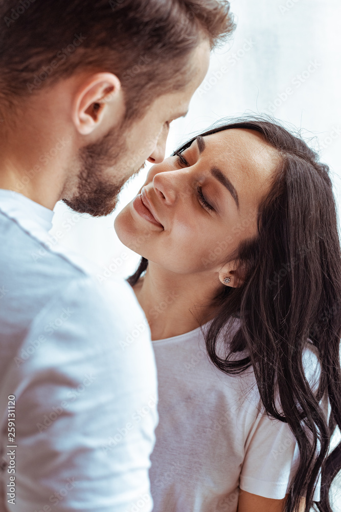 handsome man and beautiful woman in t-shirt looking at each other and kissing