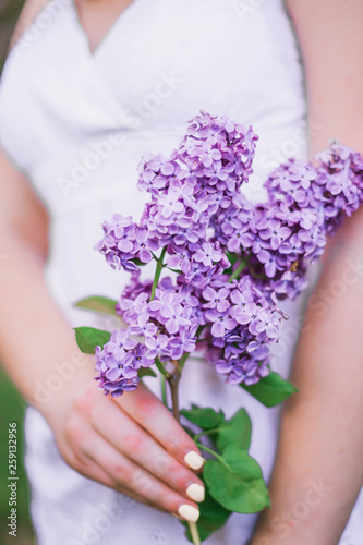 Girl holds n her hands a branch of blossoming lilacs