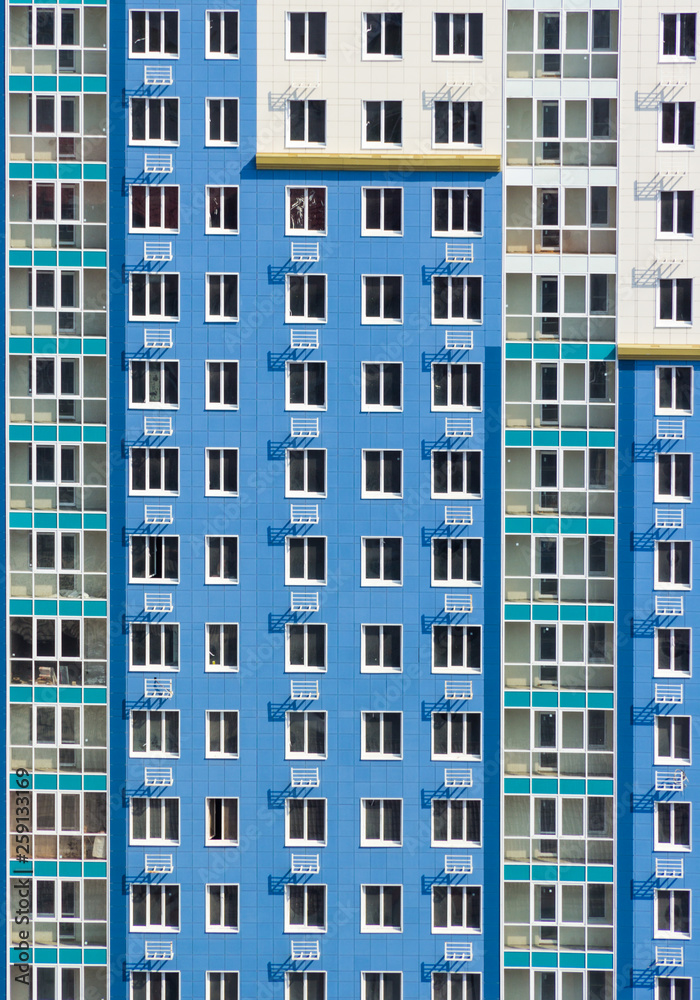 High-rise wall with windows. Multi-storey building. Blue house background with windows