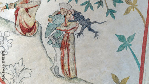 Medieval church fresco from Odsherred in denmark. A young couple embraces each other while a devil sits on the woman shoulder and whispers trying to make er break the commandment about adultery.