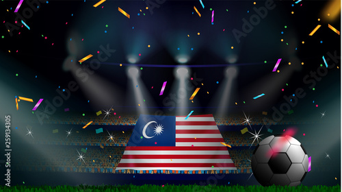 Photography Fans hold the flag of Malaysia among silhouette of crowd audience in soccer stadium with confetti to celebrate football game
