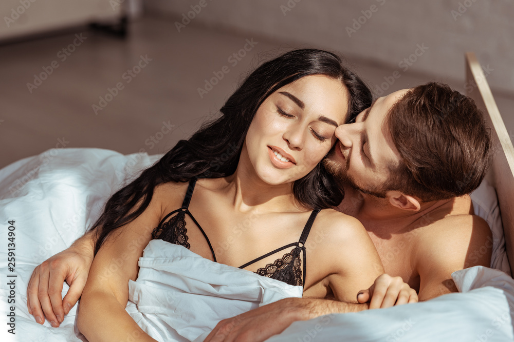 handsome man lying and hugging beautiful woman in bra in bedroom handsome man lying and hugging beautiful woman in bra in bedroom