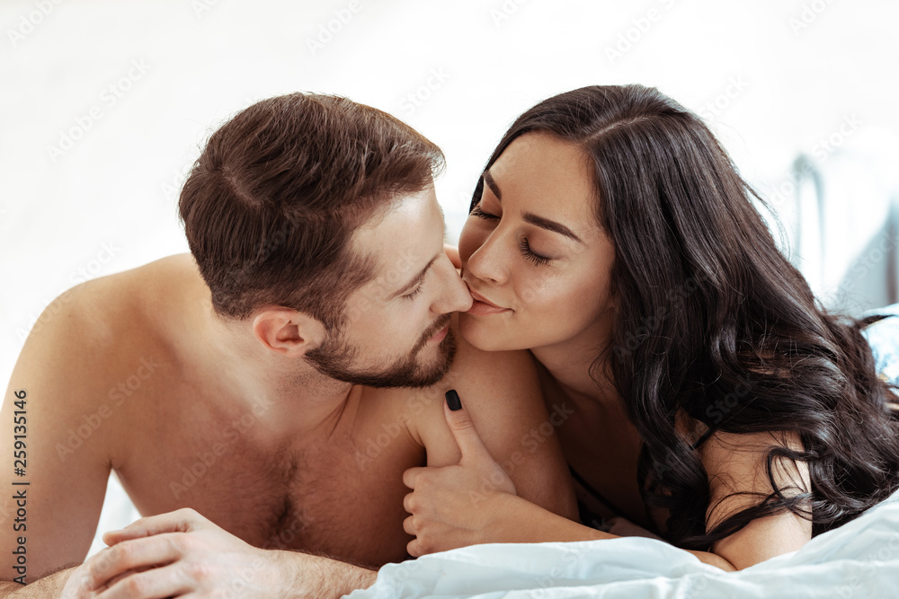 handsome man lying on bed and kissing with beautiful woman in bedroom handsome man lying on bed and kissing with beautiful woman in bedroom