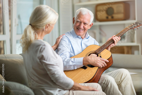 Senior man playing guitar for his wife