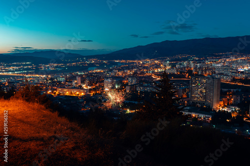 aerial view, night cityscape view with night sky. natural clear view with fireworks over big city blocks with street lights and hills around - Image
