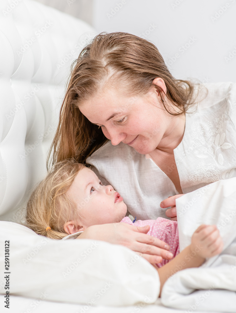 happy mother with baby  lying on bed at home