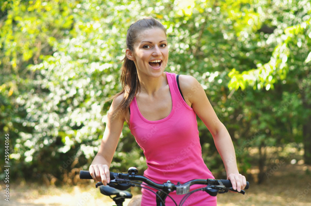 Young sporty woman walking in Park with a bicycle.	