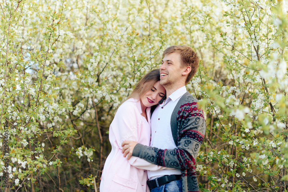 a young couple in love cuddles against the background of blooming spring cherry orchards 1 a young couple in love cuddles against the background of blooming spring cherry orchards 1